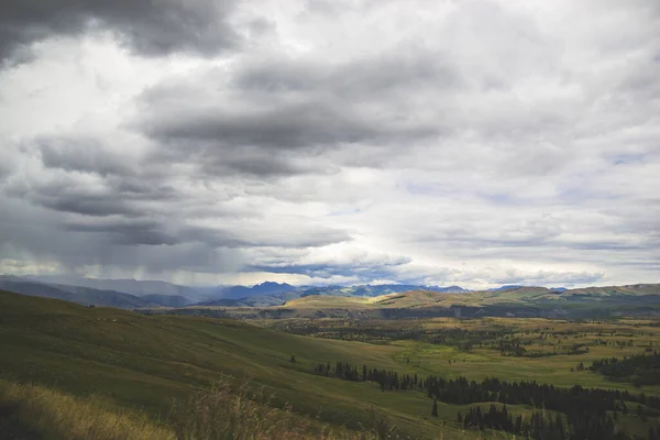 Rainy and sunny weather in Yellowstone national park. Landscape view of hills, green grass, forest and cloudy sky. National parks in United States.