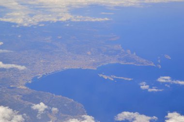 İspanya 'nın bir kısmındaki uçak penceresinden hava görüntüsü. Bulutlu mavi deniz ve tepelerde büyük şehirler. Denizde küçük bir ada. Tatilden kalan hafıza kartı. 