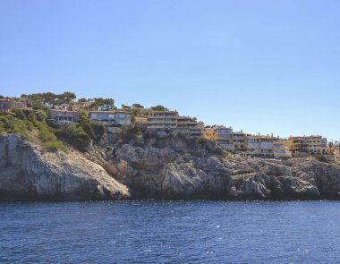Palma de Mallorca 'da küçük sarı evleri olan taş plaj manzarası. Mavi gökyüzü ve denizin ana rengi sarı tonda. Tatilden kalan hafıza kartı. İspanya 'nın Bir kısmı. 