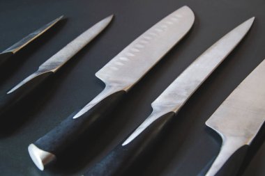 Karanlık arka planda bıçak seti. Ürünler için mutfak aletlerinin resmini kapat. Hazırlık için metal ekipman. Uzayı kopyala Yaratıcı düzen. Şef, restoran ya da mutfak konsepti. Üst görünüm.