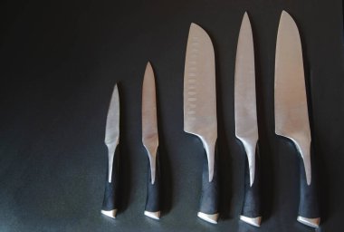 Karanlık arka planda bıçak seti. Ürünler için mutfak aletlerinin resmini kapat. Hazırlık için metal ekipman. Uzayı kopyala Yaratıcı düzen. Şef, restoran ya da mutfak konsepti. Üst görünüm.