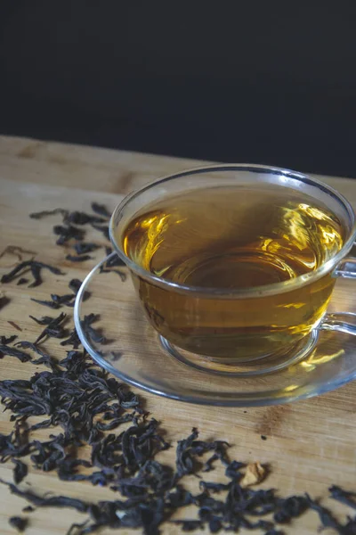 Close up picture cup of tea with dry leaves on the side on wooden background, flat lay composition with empty space for text. Aroma beverage for evening, tea time of chillness, natural taste.