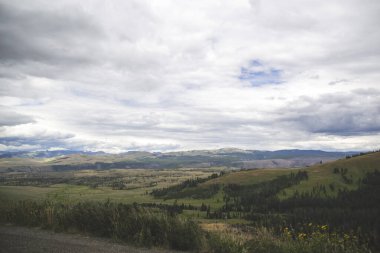Yellowstone Ulusal Parkı 'nda bulutlar ve yeşil alanlarla kaplı tepe manzarası. Gezginler için duvar kağıdı konsepti ve kopyalanmış yer. Dünyanın en ünlü doğal güzelliği.