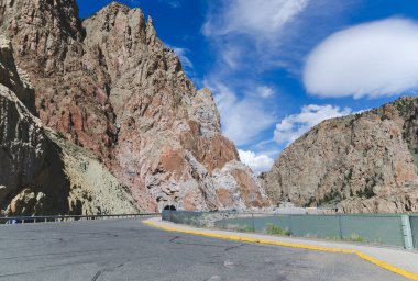 Buffalo Bill Reservoir yakınlarında yol manzaralı ve mavi gökyüzü arka planlı büyük kahverengi dağlar. Wyoming 'deki tünelden geçerek Yellowstone parkına giden yol ABD' de turistik dönüm noktası olan doğa kavramı.