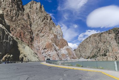 Big brown mountains near Buffalo Bill Reservoir with road view and blue sky background. Road trough the tunnel in Wyoming on way to Yellowstone park, nature concept of  touristic landmark in USA clipart