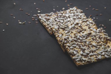 Üzerinde ayçiçeği ve chia tohumu olan kurabiyelerin resmini kapatın. Bu tohumlar, doğal içerikli ve şekersiz sağlıklı tatlıların siyah zeminine yerleştirilmiştir. Ev yapımı duvar kağıdı kopyalama alanı gibi. 