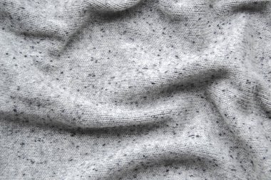 Moda endüstrisi için eski moda konsepti ile duvar kağıdı olarak küçük tutacakları ev yapımı örgü giysiler gibi doğal yünden küçük sırtı olan gri süveter resmini kapat