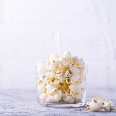 Beyaz arka plan üzerinde cam kase patlamış mısır.