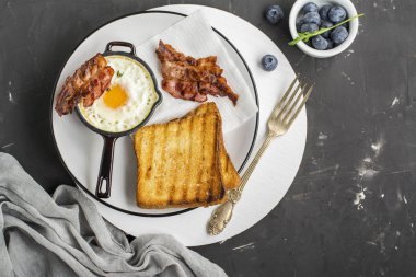 Kahvaltı Seti. Pan kızarmış yumurta pastırma ve siyah arka plan üzerine taze yaban mersini ile,