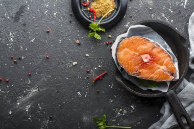 Muhteşem deniz Kuzey somon baharatlarla pişirmeden önce porsiyon ve dökme demir şeklinde koyu arka plan üzerinde tuz. Üstten Görünüm