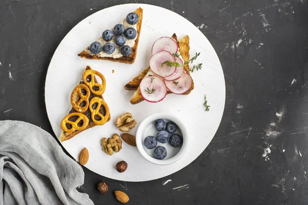 मूंगफली का मक्खन और ब्लूबेरी, चॉकलेट पास्ता बिस्कुट, बोर्ड फ़ीड पर पनीर दही मूली के साथ नाश्ते के लिए मिश्रित सैंडविच। शीर्ष दृश्य — स्टॉक फ़ोटो, इमेज