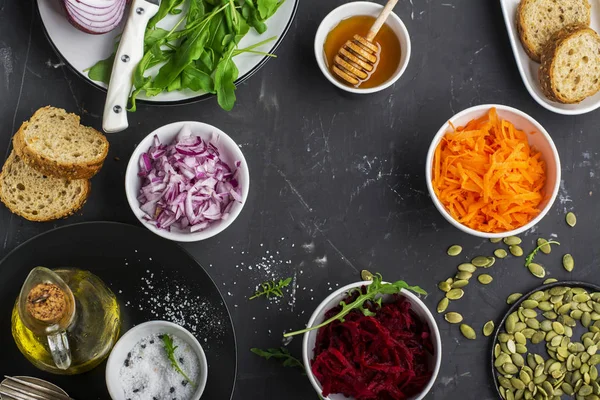 Gezonde vegetarische ingrediënten wortelen, bieten, rode ui, rucola voor frisse salade salades — Stockfoto