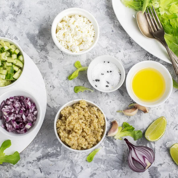 Ingrediënten voor een lichte salade van quinoa, komkommer, kaas en zoete rode ui met boter sla op grijze achtergrond. Bovenaanzicht. Groen — Stockfoto