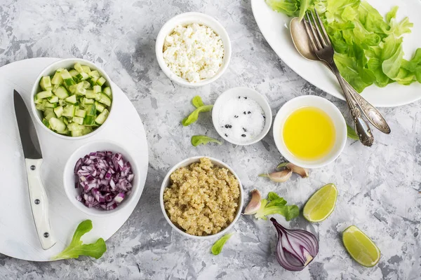 Ingredienser för en lätt sallad quinoa, gurka, ost och söt rödlök med smör sallad på grå bakgrund. Ovanifrån. Grönska — Stockfoto