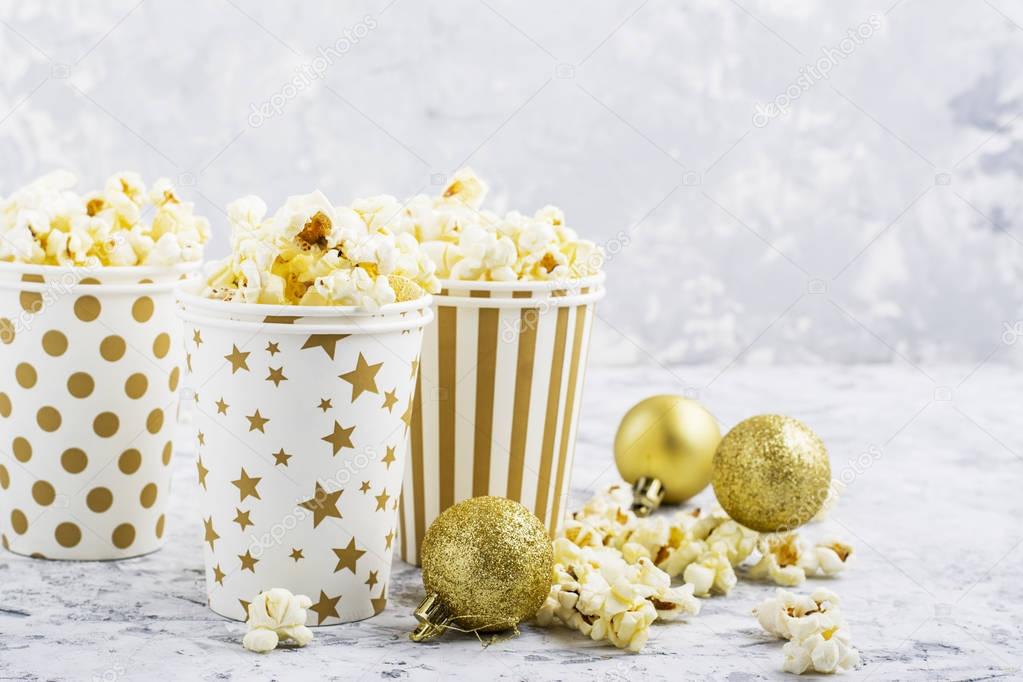 Salty fresh crusty homemade popcorn in paper cup in the fashion light background of white brick wall in a New Year's interior with Christmas balls. selective focus