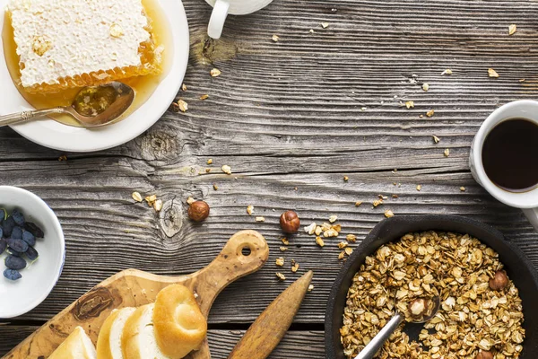Υγιεινό πρωινό. Μέλι τραγανή flavorful granola με ξηρούς καρπούς και μούρα φρέσκα λουλούδια σε ξύλινα γκρίζο φόντο. επιλεκτική εστίαση — Φωτογραφία Αρχείου