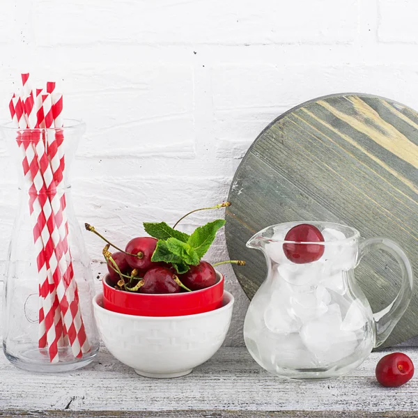 Kitchen still life white brick wall: kitchen utensils, cutting board, ice cubes for cocktails, berries, cocktail tubes for a holiday in the backyard. In the horizontal