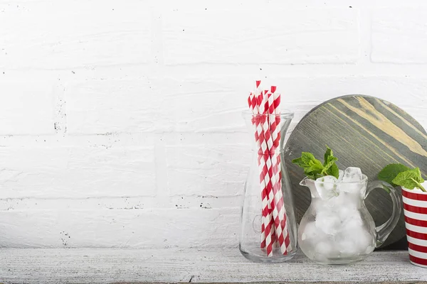 Kitchen still life white brick wall: kitchen utensils, cutting board, ice cubes for cocktails, berries, cocktail tubes for a holiday in the backyard. In the horizontal