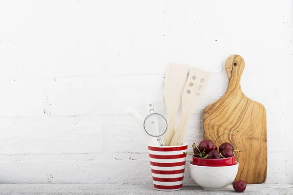 A simple kitchen still life against a white brick wall: cutting board, cooking equipment, ceramics. Horizontal — Stock Photo, Image