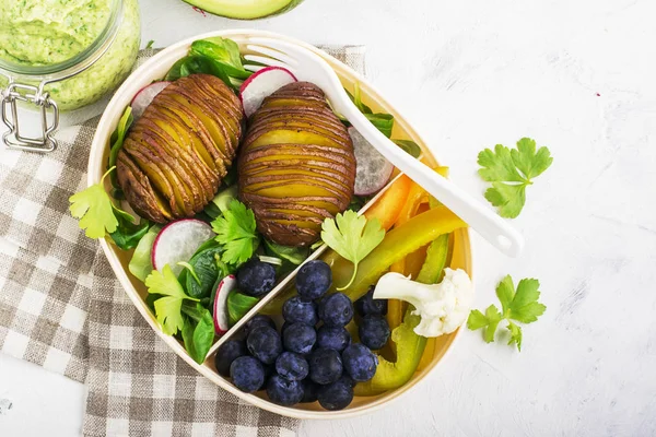 Collation santé dans une boîte à lunch : pommes de terre dorées, salade, bleuets, poivron vert, chou-fleur, radis dans un récipient en plastique avec une fourchette. Vue du dessus — Photo