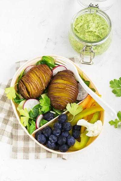 Collation santé dans une boîte à lunch : pommes de terre dorées, salade, bleuets, poivron vert, chou-fleur, radis dans un récipient en plastique avec une fourchette. Vue du dessus — Photo