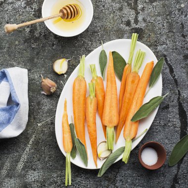 Genç sulu havuç pişmiş tatlım, adaçayı, sarımsak, zeytinyağı, tuz ve arka plan üzerinde kendinizi evinizde gibi hissedeceğiniz rahat yemek için. Üstten Görünüm.