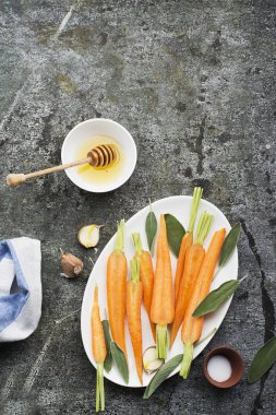 Genç sulu havuç pişmiş tatlım, adaçayı, sarımsak, zeytinyağı, tuz ve arka plan üzerinde kendinizi evinizde gibi hissedeceğiniz rahat yemek için. Üstten Görünüm.