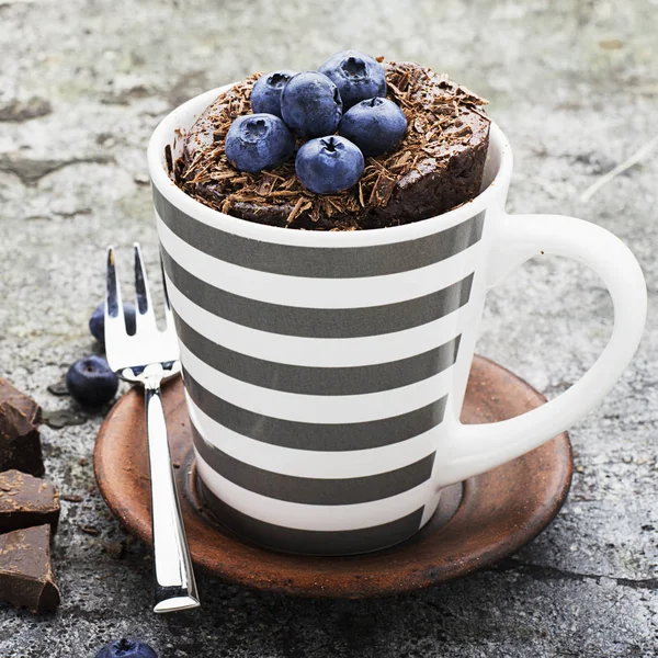 Petit déjeuner sain ou collation. cupcake tasse chocolat aux myrtilles et pépites de chocolat dans une tasse en céramique rayée grise sur un fond de pierre grise. Concentration sélective . — Photo