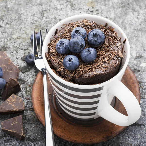 Petit déjeuner sain ou collation. cupcake tasse chocolat aux myrtilles et pépites de chocolat dans une tasse en céramique rayée grise sur un fond de pierre grise. Concentration sélective . — Photo