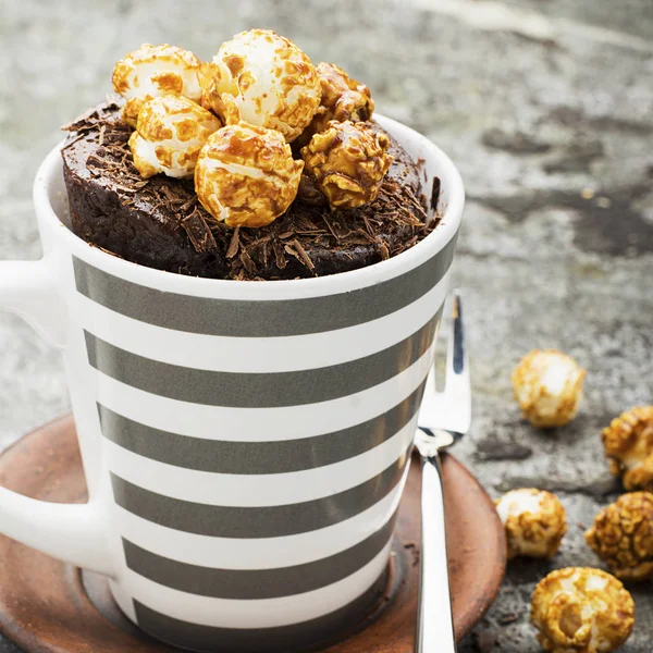 Gâteau de tasse aromatique au chocolat avec pop-corn appétissant au caramel pour un thé chaud confortable d'automne buvant sur un fond de pierre grise dans une tasse rayée grise élégante. Concentration sélective . — Photo