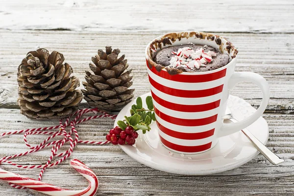 Een mok taart voor een feestelijke oudejaarsavond snack met rood witte snoepjes in een gestreepte rode witte mok op een grijze steen achtergrond met winter parafernalia. Selectieve aandacht. — Stockfoto