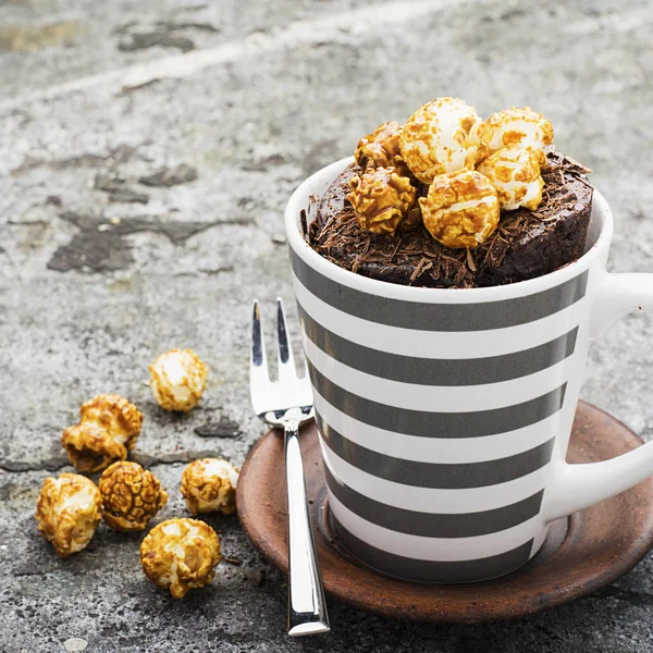 Gâteau de tasse aromatique au chocolat avec pop-corn appétissant au caramel pour un thé chaud confortable d'automne buvant sur un fond de pierre grise dans une tasse rayée grise élégante. Concentration sélective . — Photo