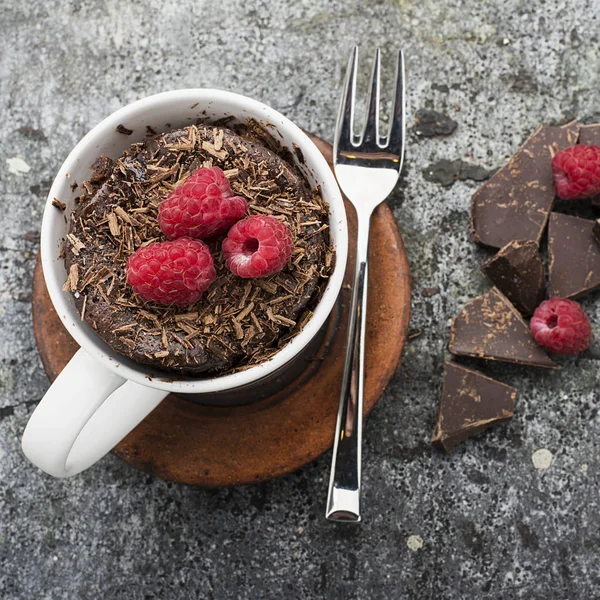 Choklad mugg hemmagjord tårta med choklad chips, saftiga färska hallon i en snygg randig grå mugg med bitar av bitter choklad på en grå sten bakgrund. Selektivt fokus. — Stockfoto