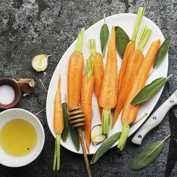 Young juicy carrots baked with honey, sage, garlic, olive oil, salt for a homely comfortable dinner on the background. Top View. — Stock Photo, Image