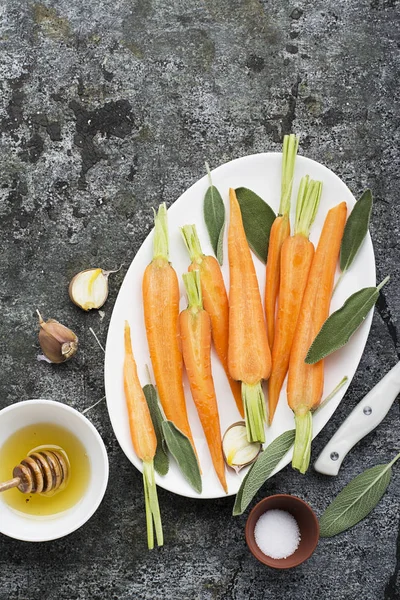 Молодые сочные морковь, шалфей, цветочный мед, чеснок, соль ингредиенты для выпечки карамели пряная морковь. Вид сверху — стоковое фото