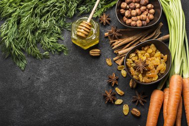 Malzemeler geleneksel klasik havuç için aromalı sonbahar mevsim pasta: sulu taze havuç, Kuru üzüm, baharatlar, baharat, tatlım, karanlık bir arka plan üzerinde fındık. Üstten Görünüm.