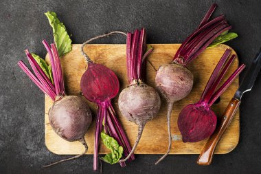 Düz siyah arka plan üzerinde bir vintage ahşap kesme tahtası üzerinde ham organik tarım pancar. Üstten Görünüm.