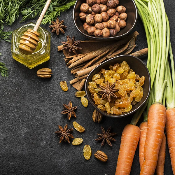 Malzemeler geleneksel klasik havuç için aromalı sonbahar mevsim pasta: sulu taze havuç, Kuru üzüm, baharatlar, baharat, tatlım, karanlık bir arka plan üzerinde fındık. Üstten Görünüm.