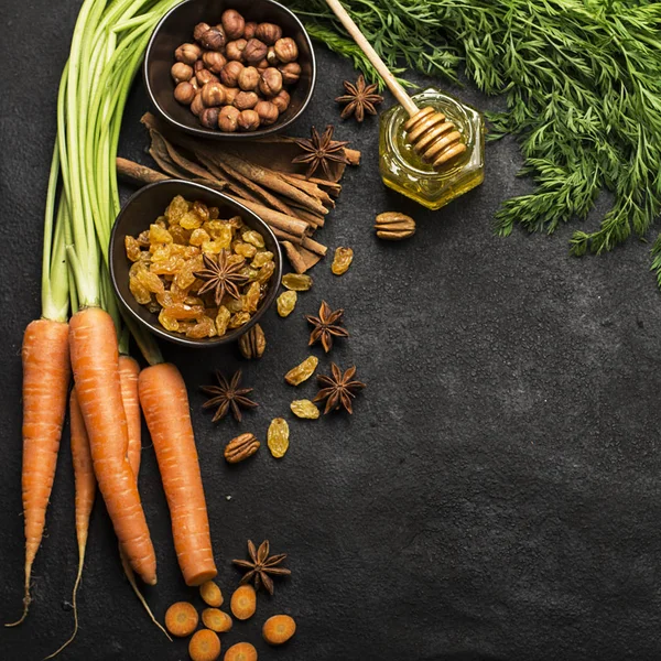 Malzemeler geleneksel klasik havuç için aromalı sonbahar mevsim pasta: sulu taze havuç, Kuru üzüm, baharatlar, baharat, tatlım, karanlık bir arka plan üzerinde fındık. Üstten Görünüm.