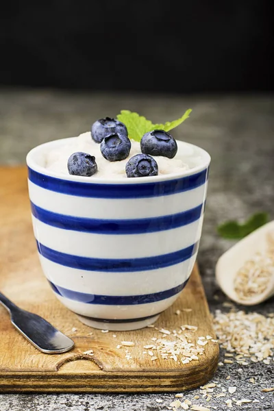 La papilla de leche del salvado de avena en las copas de porcelana con los arándanos frescos jugosos. Alimento dietético. Enfoque selectivo —  Fotos de Stock