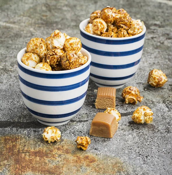 İki seramik beyaz çizgili mavi kase şık gri taş zemin üzerine tatlı karamelli patlamış mısır. Seçici odak.