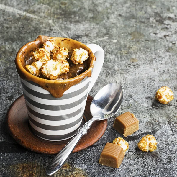 Un mug cupcake au chocolat et caramel salé dans une tasse en céramique rayée grise sur un simple fond gris. Concentration sélective. Snack pendant cinq minutes au micro-ondes . — Photo