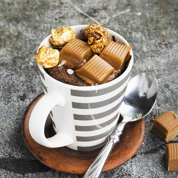 Un mug cupcake au chocolat et caramel salé dans une tasse en céramique rayée grise sur un simple fond gris. Concentration sélective. Snack pendant cinq minutes au micro-ondes . — Photo