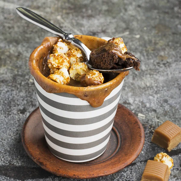 Kupa çörek çikolata ve tuzlu karamel basit bir gri arka plan üzerine bir gri çizgili seramik kupa ile. Seçici odak. Mikrodalga beş dakikalığına snack.