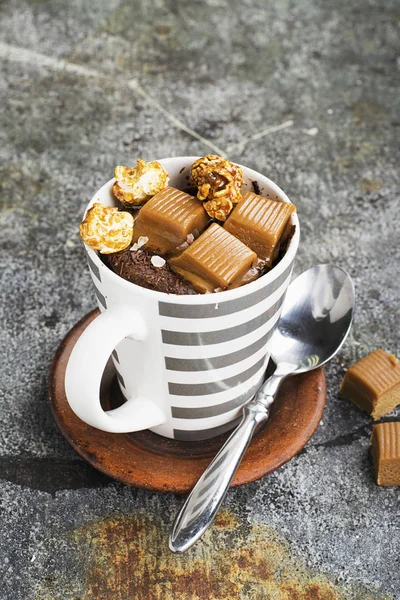 Un mug cupcake au chocolat et caramel salé dans une tasse en céramique rayée grise sur un simple fond gris. Concentration sélective. Snack pendant cinq minutes au micro-ondes . — Photo