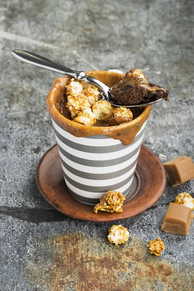 Un mug cupcake au chocolat et caramel salé dans une tasse en céramique rayée grise sur un simple fond gris. Concentration sélective. Snack pendant cinq minutes au micro-ondes . — Photo