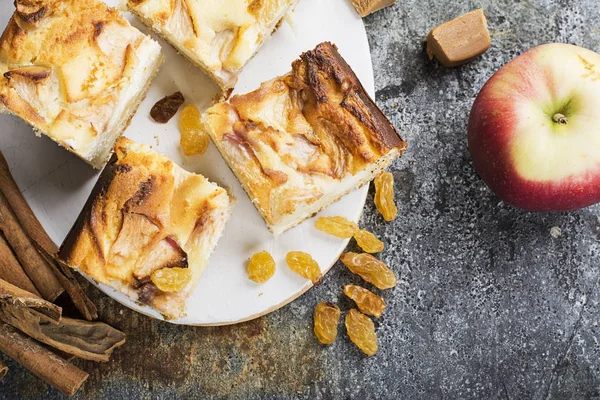 Basit bir ev yapımı pasta elma ve tarçın, bir elma, karamel tatlılar ile gri bir arka plan üzerinde ekşi krema ile. Üstten Görünüm. Seçici odak.