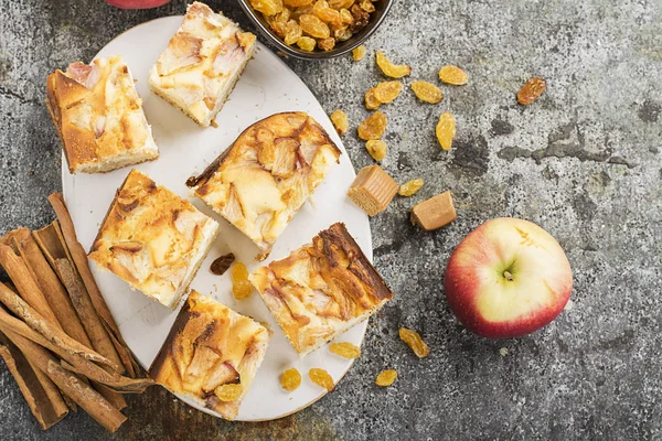 Basit bir ev yapımı pasta elma ve tarçın, bir elma, karamel tatlılar ile gri bir arka plan üzerinde ekşi krema ile. Üstten Görünüm. Seçici odak.