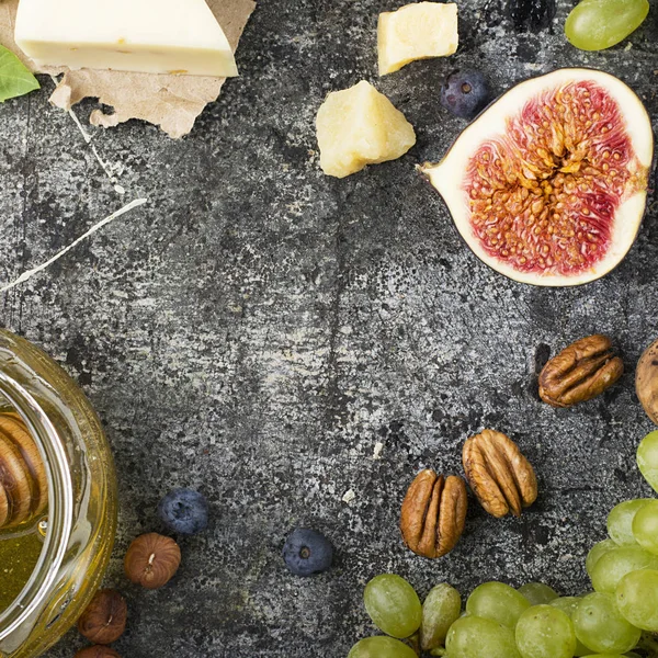 Tabla de quesos para snacks, trucos, reuniones con amigos, sobre un fondo de piedra gris: quesos variados, queso joven, parmesano, queso con alholva, higos, nueces, miel, uvas Top View . —  Fotos de Stock