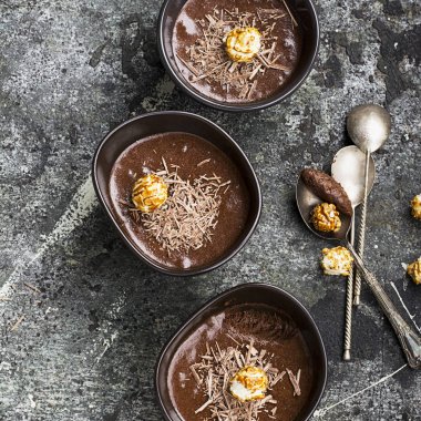 Hassas tatlı çikolata mousse çikolata yaptı rahat bir sonbahar cips ve porselen karanlık içinde karamelli patlamış mısır basit bir gri taş zemin üzerinde kase. Üstten Görünüm.